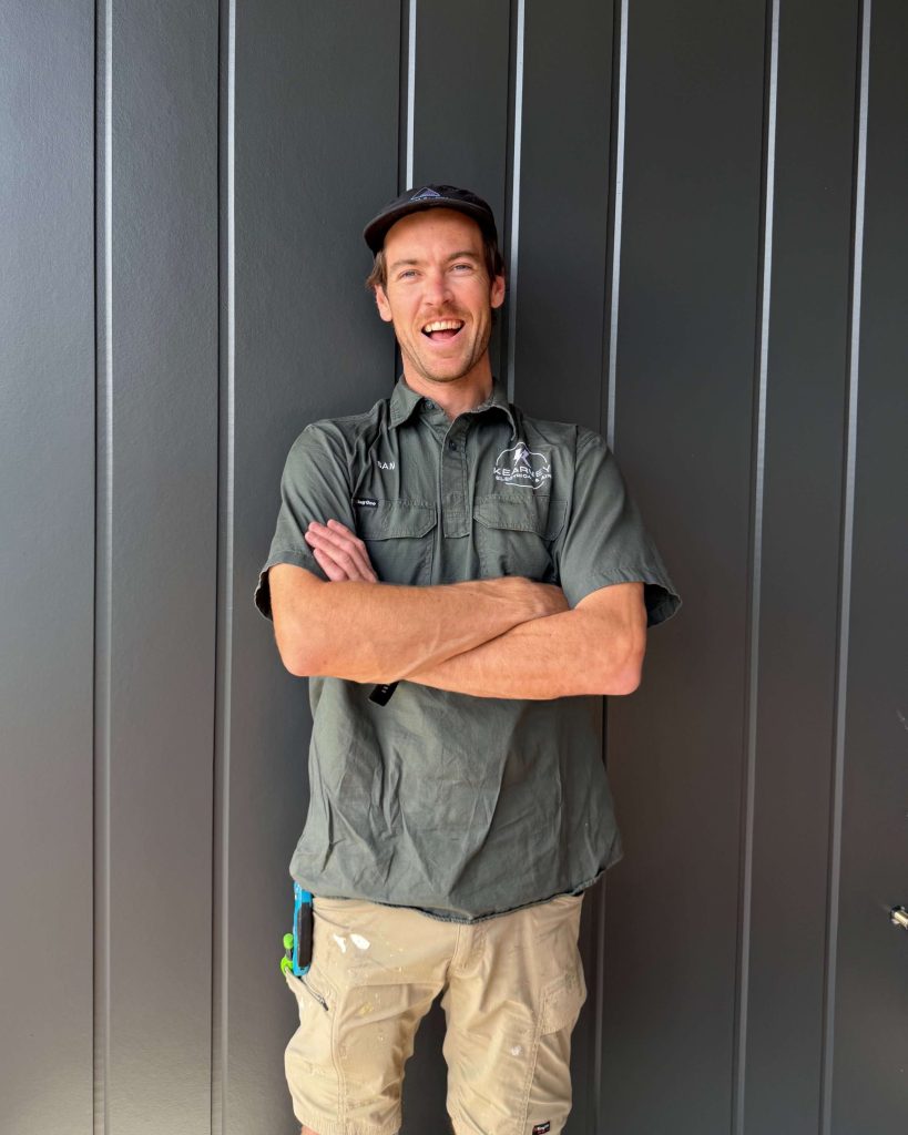 Sam Kearney standing against charcoal wall